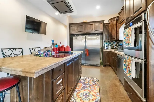 a kitchen with stainless steel appliances granite countertop a refrigerator a stove and a sink