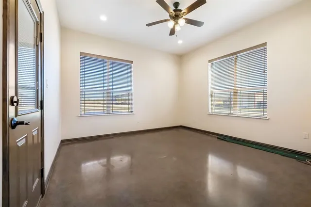 an empty room with windows and fan