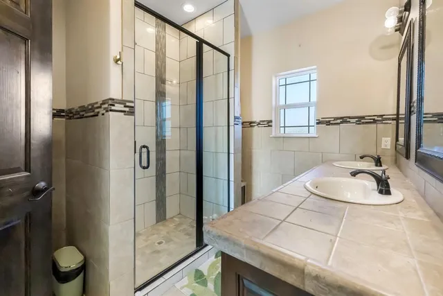 a bathroom with a granite countertop sink a mirror and shower