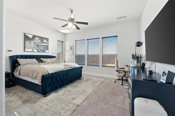 a spacious bedroom with a bed a table and windows