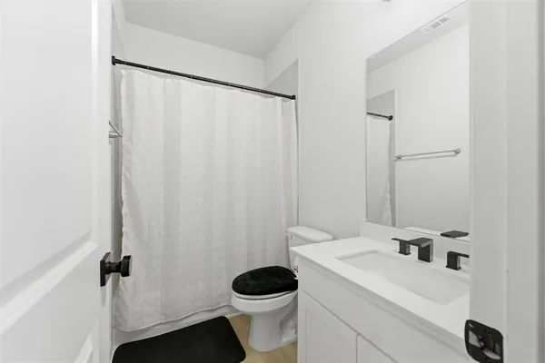 a bathroom with a sink a toilet and shower curtain
