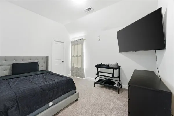 a bedroom with a bed and a flat tv screen on a dresser
