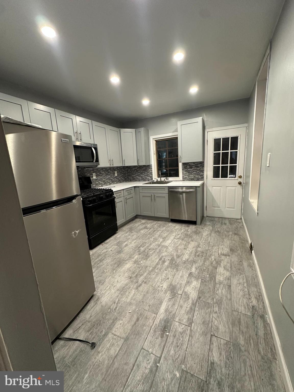 a kitchen with kitchen island a counter top space stainless steel appliances a sink and a window