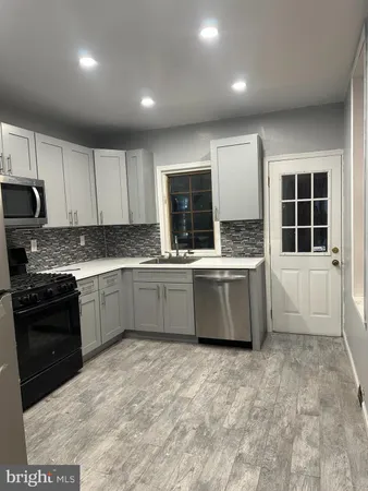 a kitchen with stainless steel appliances a sink a stove a microwave a sink a refrigerator and cabinets