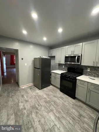 a kitchen with granite countertop a refrigerator and a stove top oven