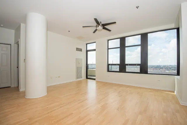 a view of an empty room with a window and wooden floor