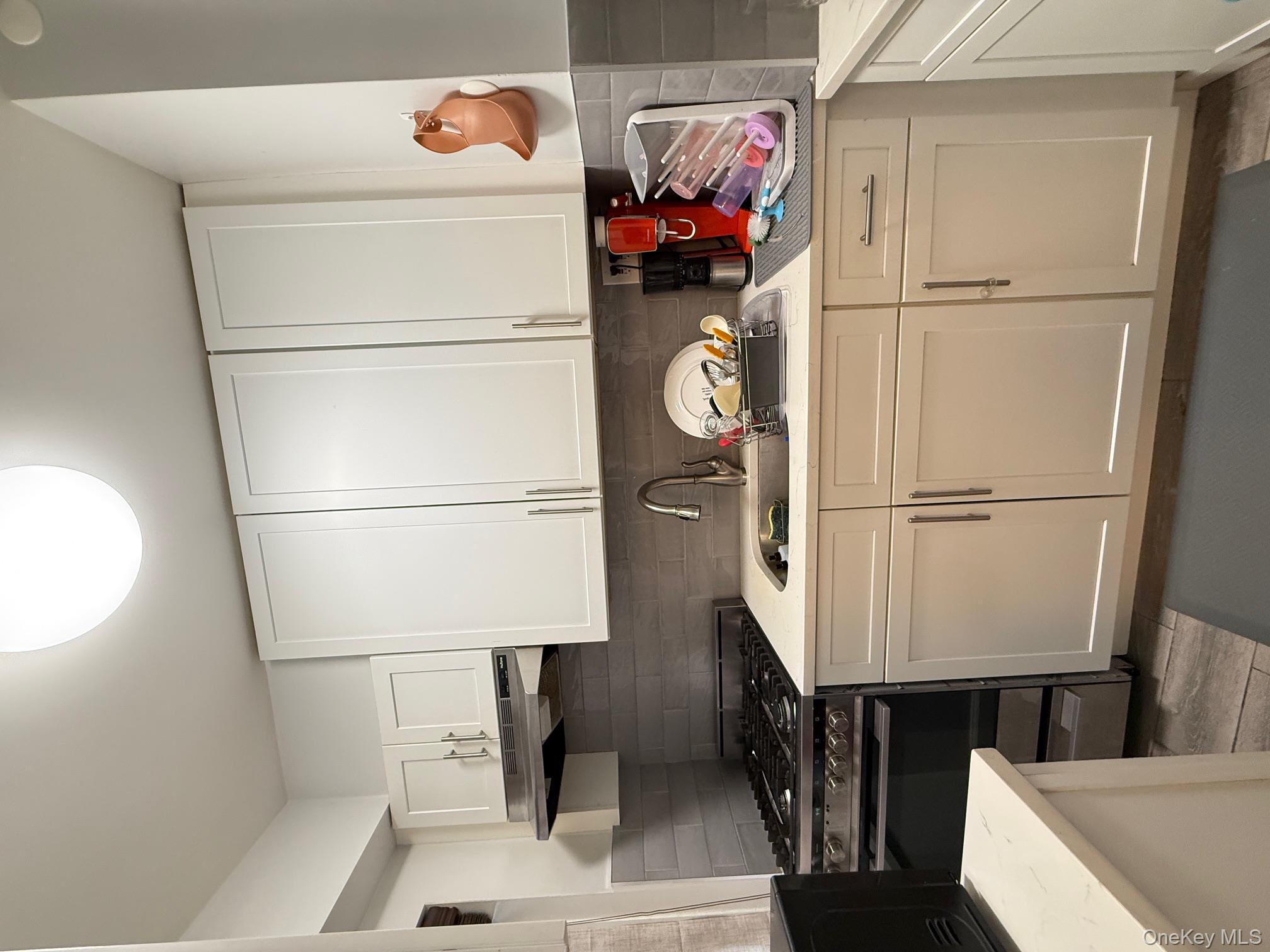 67-40 Yellowstone Boulevard, Unit 2O Queens, NY 11375 - Photo 4 of 12 a kitchen with white cabinets and appliances