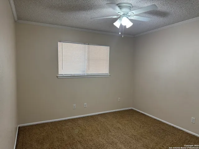an empty room with a window and a fan