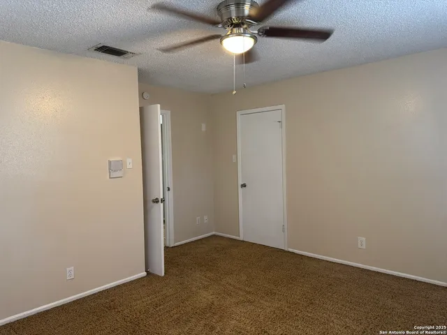 an empty room with a chandelier fan and closet area