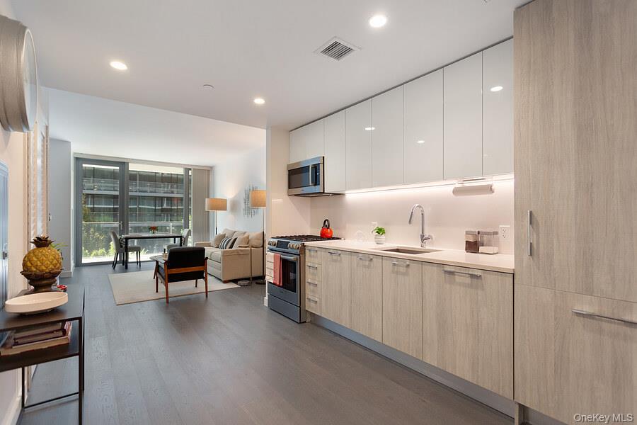 131-03 40 Road, Unit 10Q Queens, NY 11354 - Photo 11 of 15 a kitchen with a sink and living room
