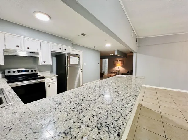 a kitchen with a refrigerator a stove top oven and white cabinets