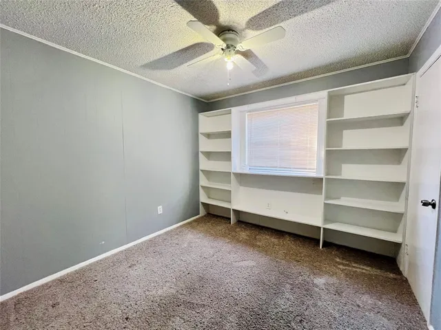an empty room with a window and a ceiling fan