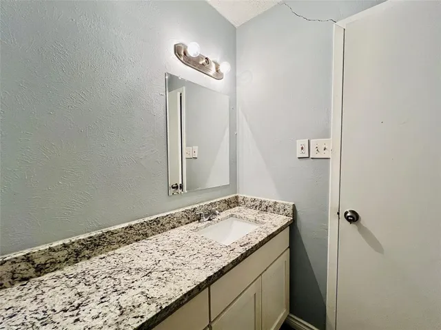 a bathroom with a granite countertop tub sink and mirror