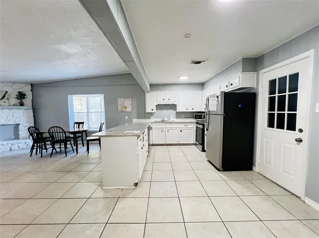 a large white kitchen with cabinets a sink a window and stainless steel appliances