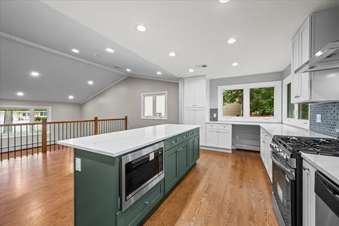 a kitchen with kitchen island granite countertop a sink stainless steel appliances and cabinets