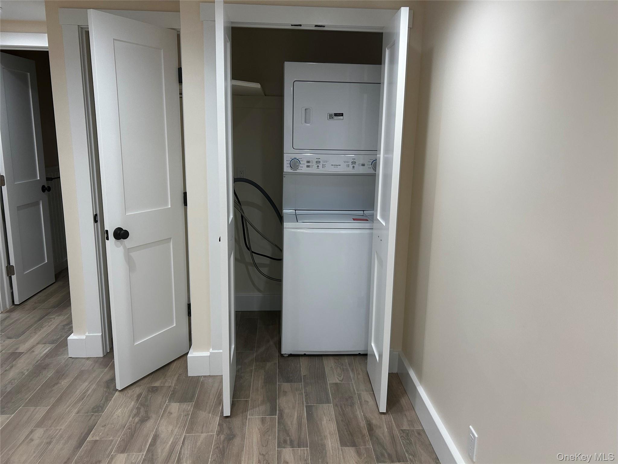 65 Linwood Road North, Unit GARDEN Port Washington, NY 11050 - Photo 11 of 11 Laundry room with wood finish floors and stacked washer / drying machine