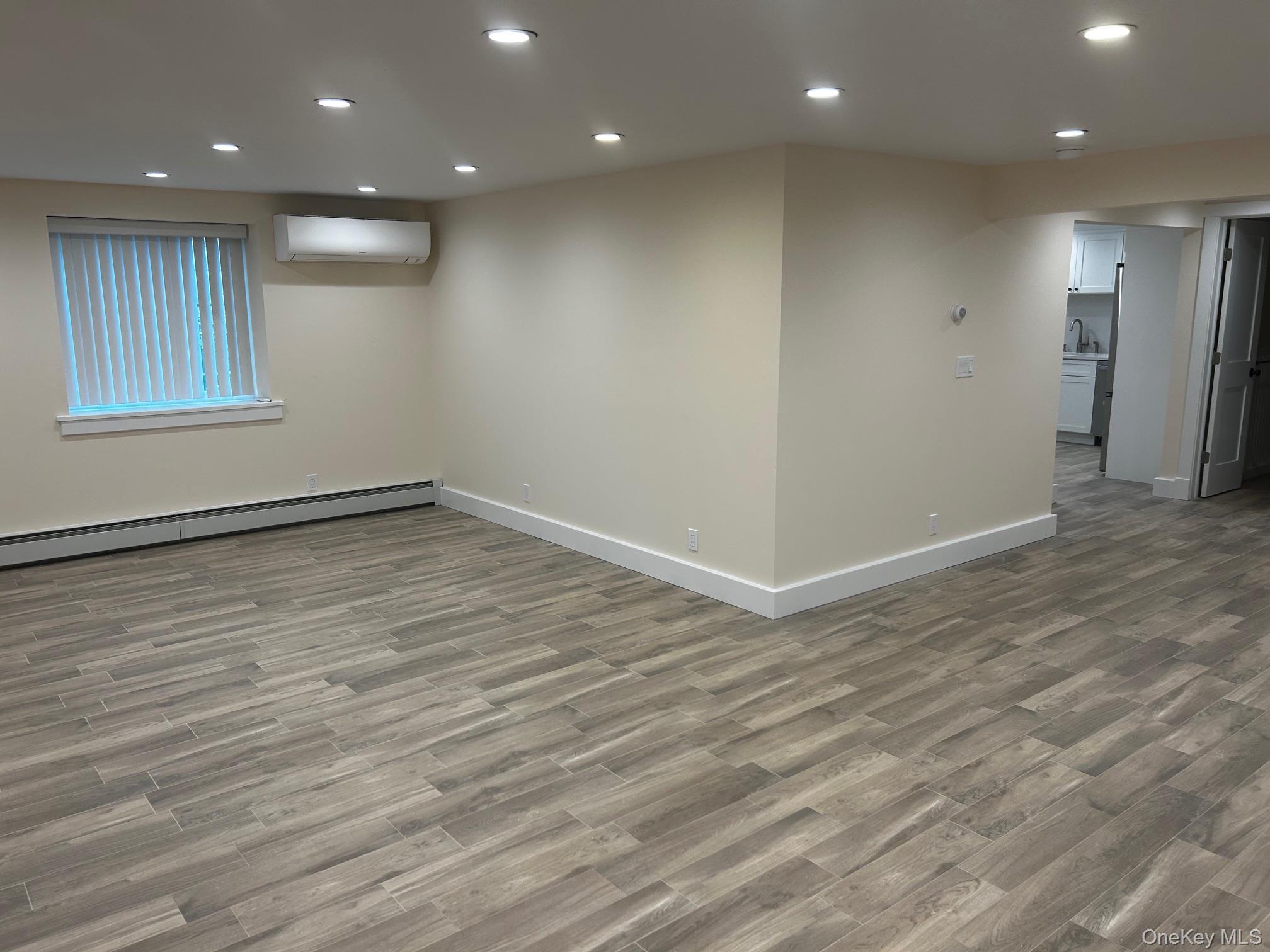 65 Linwood Road North, Unit GARDEN Port Washington, NY 11050 - Photo 2 of 11 Living room with recessed lighting, dark wood finished floors, a wall mounted air conditioner, and a baseboard heating unit