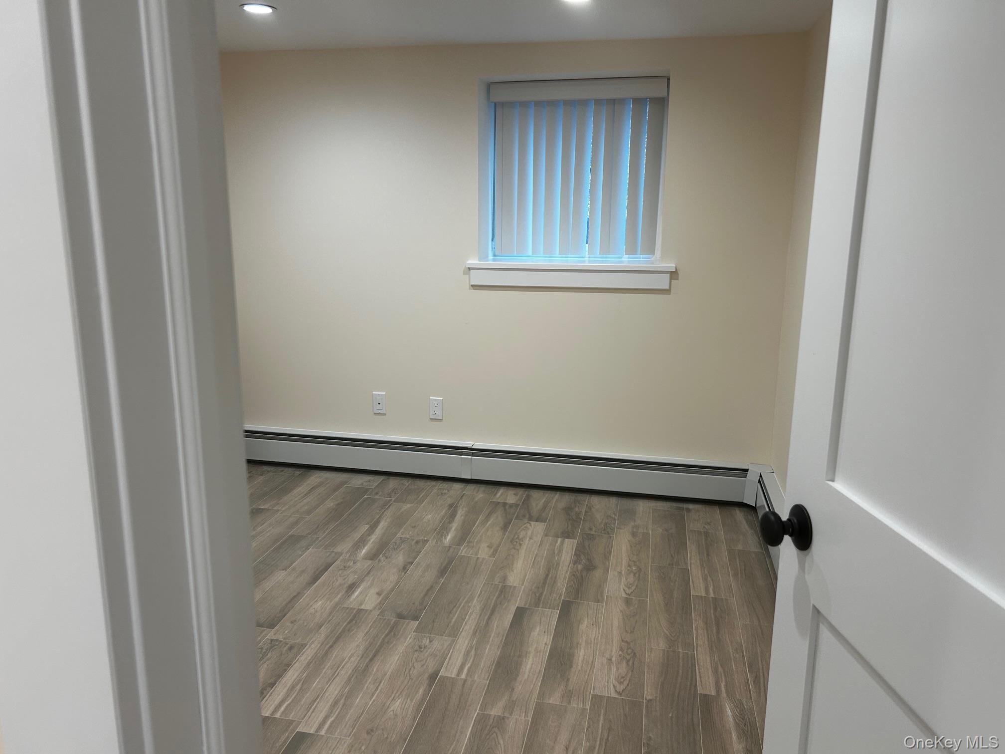 65 Linwood Road North, Unit GARDEN Port Washington, NY 11050 - Photo 9 of 11 Bedroom featuring wood finished floors, a baseboard heating unit, and recessed lighting