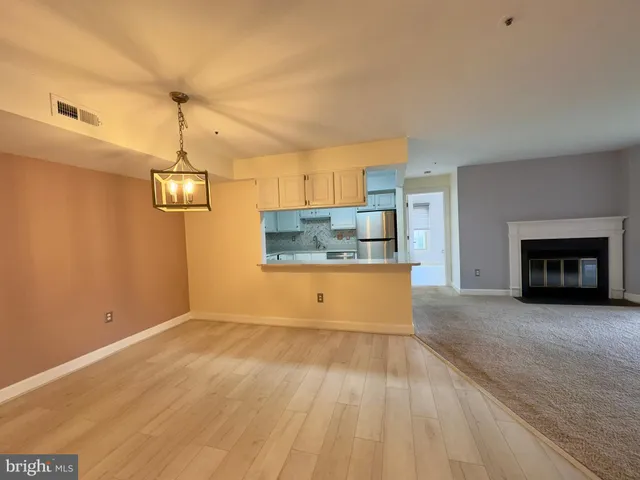 a view of kitchen and empty room with wooden floor