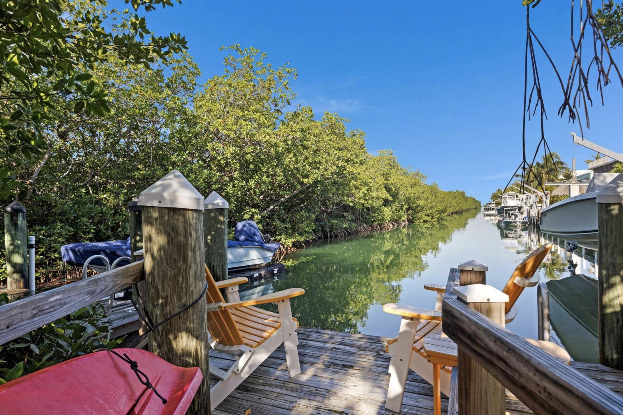 102 Venetian Drive Islamorada, FL 33036 - Photo 26 of 29 a view of a patio with table and chairs potted plants with wooden floor and fence