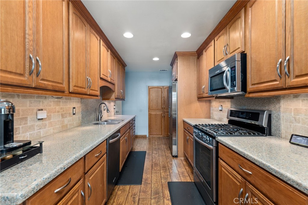 7221 Ramona Avenue Rancho Cucamonga, CA 91701 - Photo 9 of 30 a kitchen with stainless steel appliances granite countertop a stove a sink dishwasher and a refrigerator with wooden cabinets
