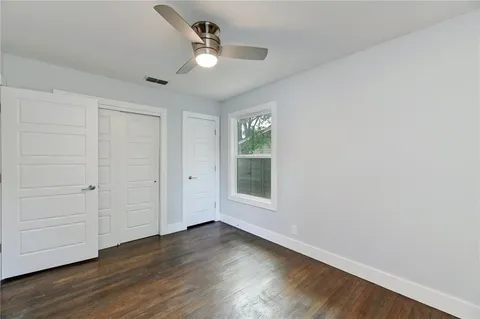 an empty room with wooden floor fan and windows