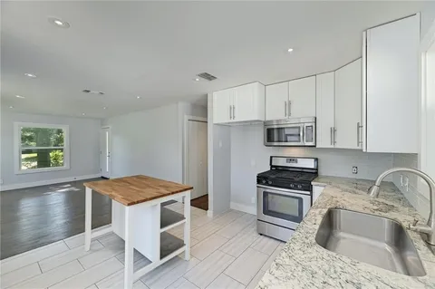 a kitchen with granite countertop a sink stove and refrigerator