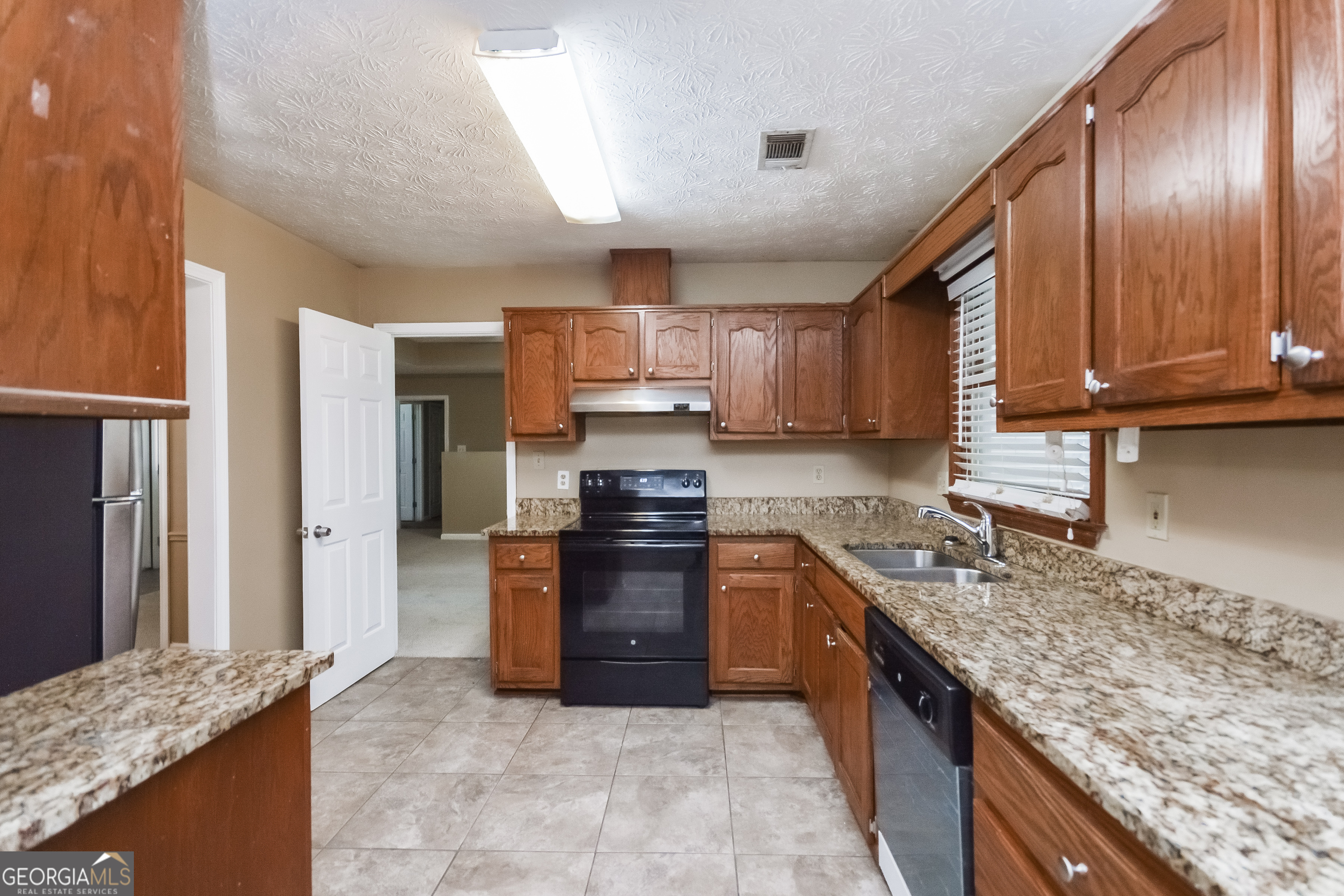 2451 Sherrie Lane Southwest Conyers, GA 30094 - Photo 7 of 17 a large kitchen with granite countertop a stove refrigerator and microwave