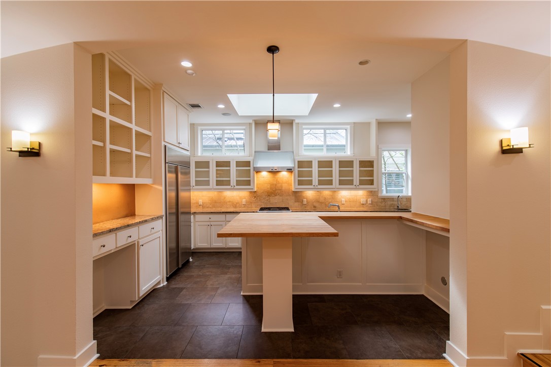 a kitchen with stainless steel appliances kitchen island granite countertop a table chairs in it and wooden floors