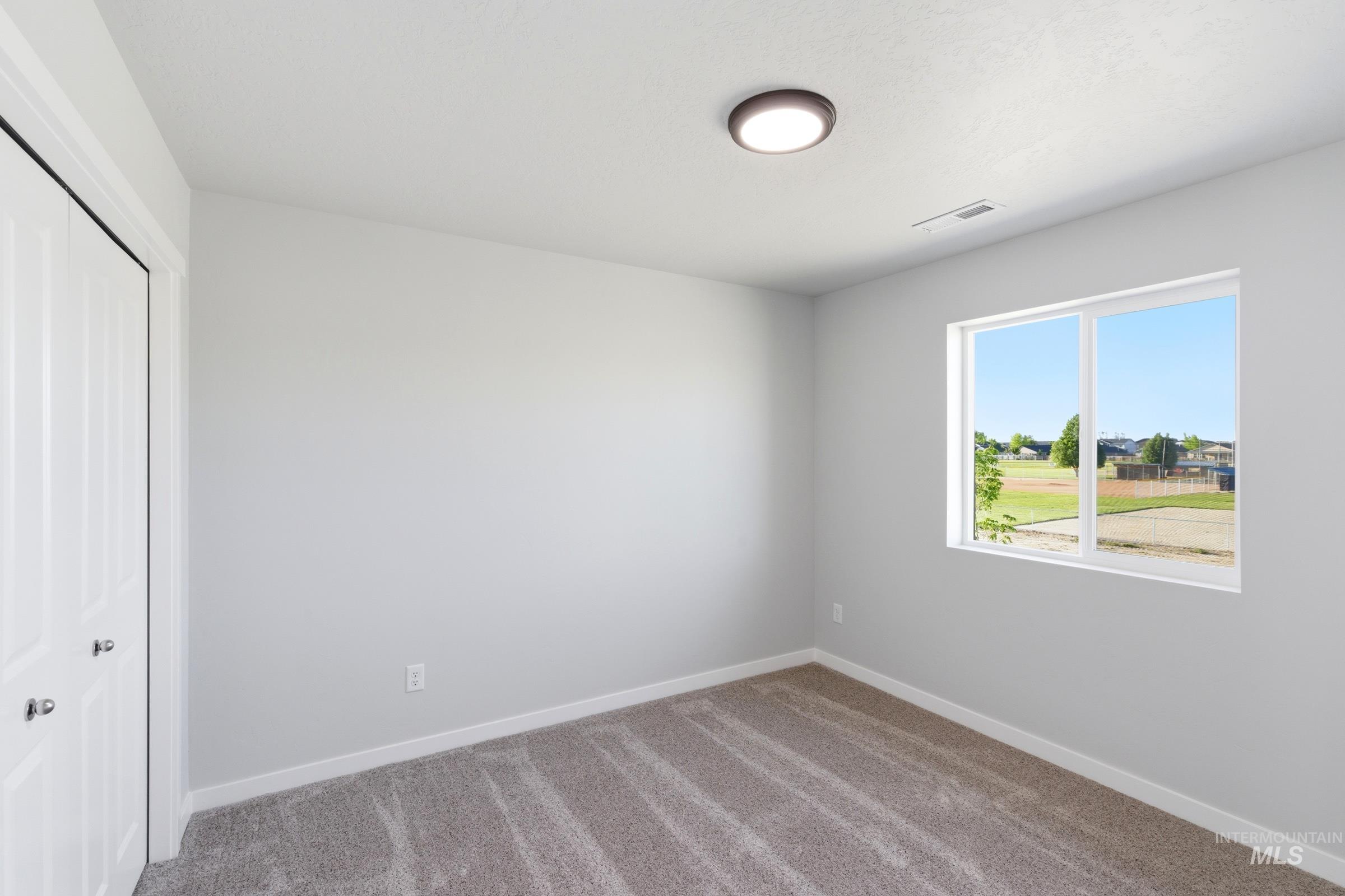 13709 Redway Court Caldwell, ID 83607 - Photo 15 of 28 Room featuring a double-pane window, flush-mount ceiling light fixture, neutral carpeting, and a bi-fold closet door