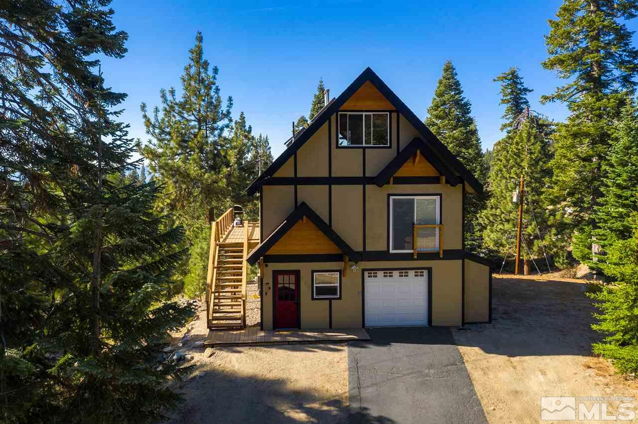 a view of a house with wooden fence and large trees