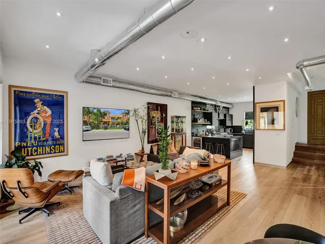 a living room with furniture a wooden floor and kitchen view