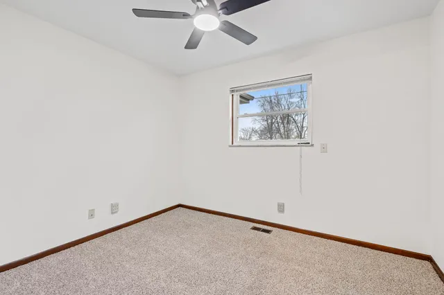 an empty room with a window and a ceiling fan