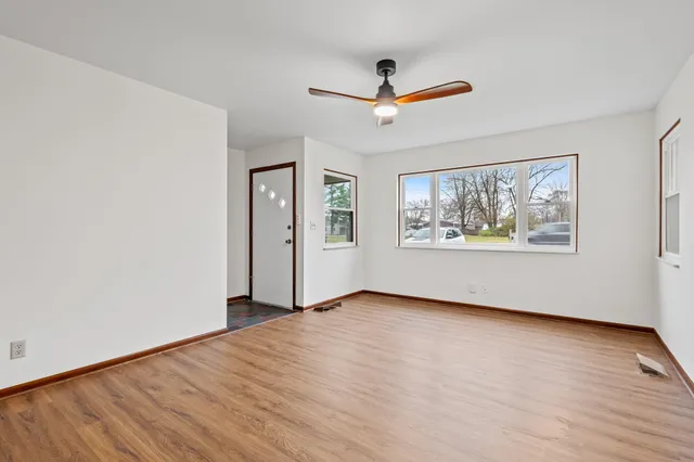 a view of an empty room with window and wooden floor