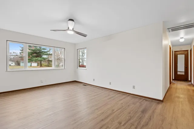 an empty room with wooden floor chandelier and windows
