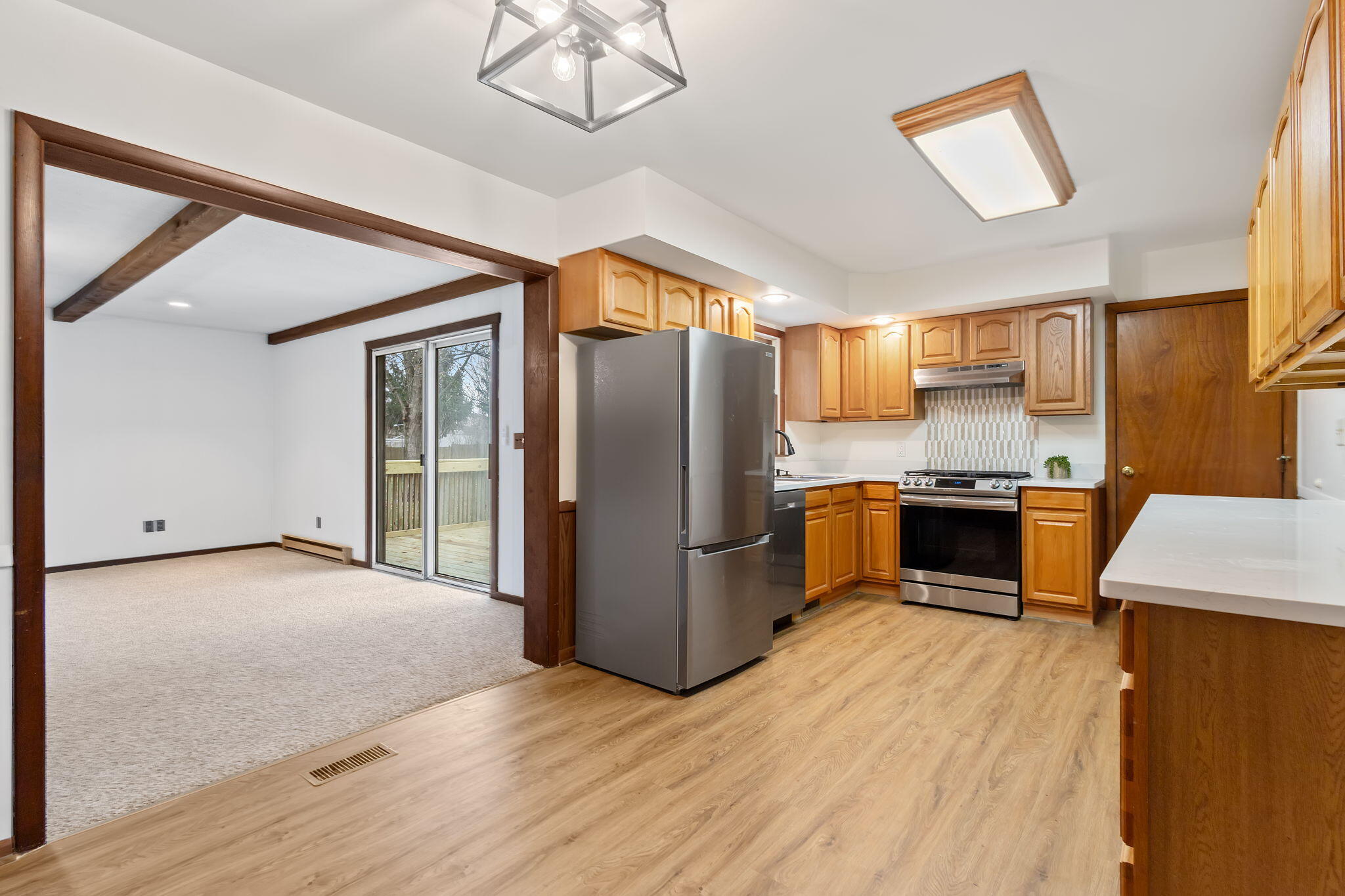 708 East Maple Street Rensselaer, IN 47978 - Photo 9 of 33 a kitchen with stainless steel appliances granite countertop a refrigerator a sink a stove a dining table and chairs with wooden floor