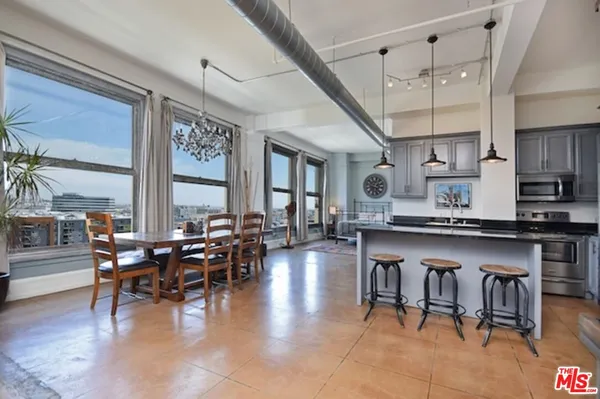 a large dining hall with stainless steel appliances granite countertop a stove a sink a dining table and chairs with wooden floor