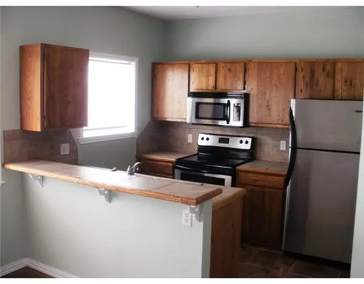 a kitchen with granite countertop a refrigerator stove top oven a sink and dishwasher