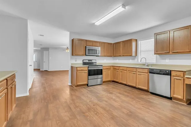 a kitchen with granite countertop a sink cabinets and stainless steel appliances