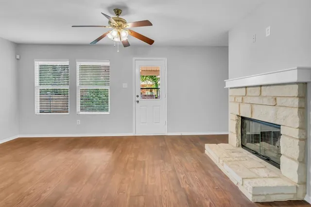 a view of empty room with wooden floor fireplace and a window