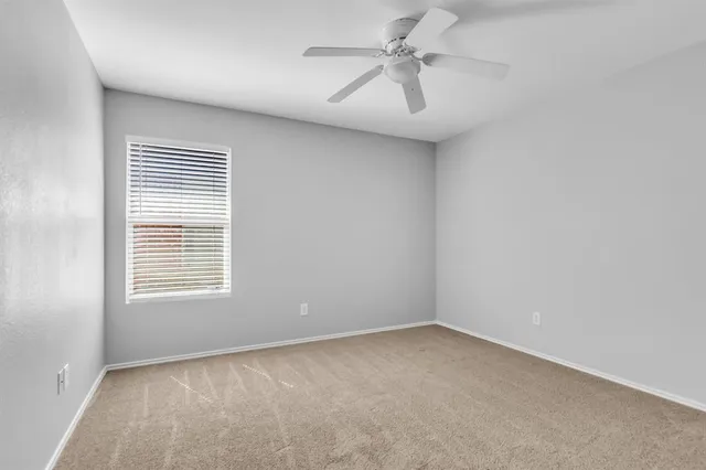 an empty room with a window and a fan