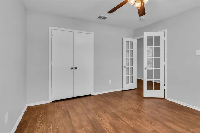 a view of empty room with wooden floor and ceiling fan