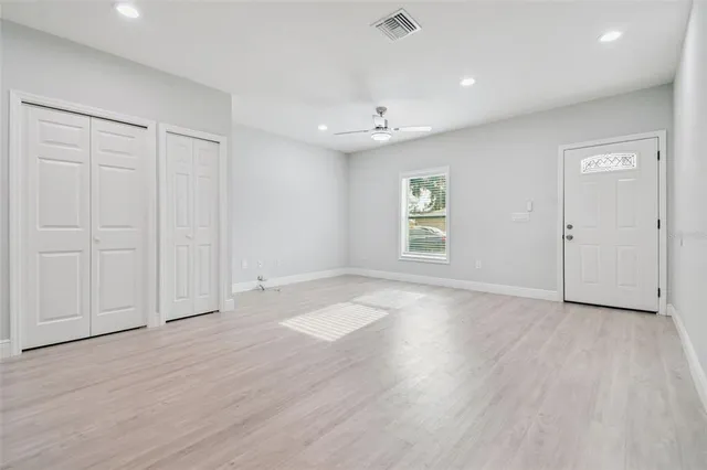 an empty room with wooden floor cabinet and windows