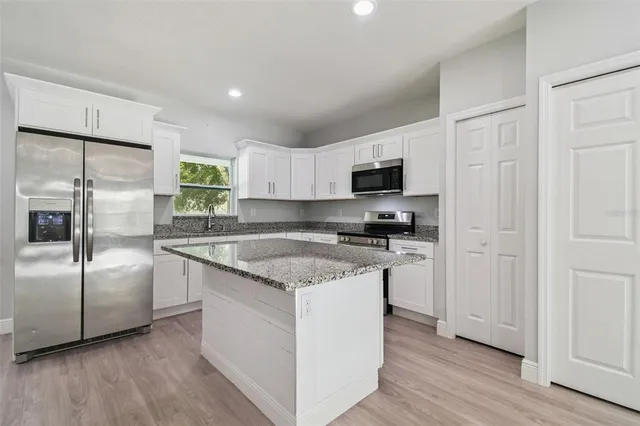 a kitchen with stainless steel appliances granite countertop a stove a sink and a refrigerator