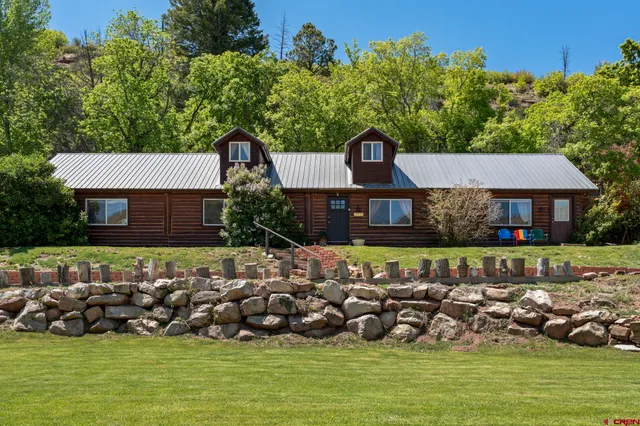 a front view of a house with a garden and lake view
