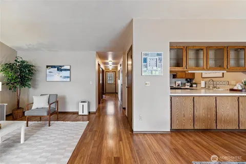 a living room with stainless steel appliances furniture a large window and a wooden floor