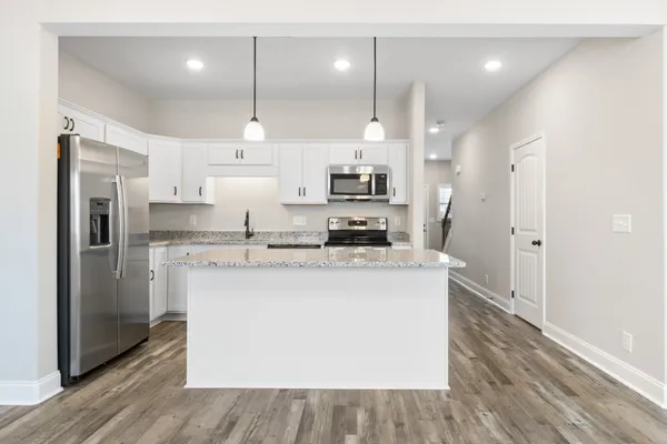 a large kitchen with stainless steel appliances kitchen island a large counter top and wooden floors