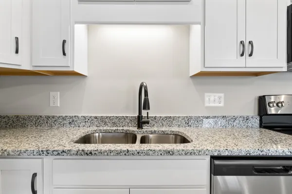 a kitchen with granite countertop white cabinets and sink