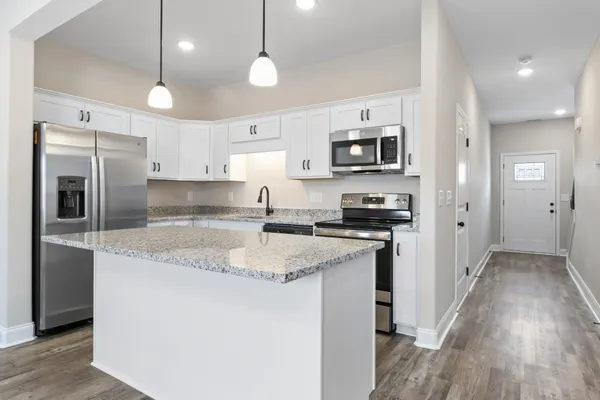 a kitchen with stainless steel appliances granite countertop a refrigerator a stove a sink and a oven