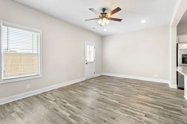 a view of an empty room with wooden floor and a window